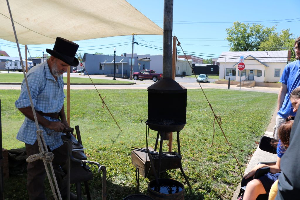 Blacksmith Station Image 2: the blacksmith is working on a piece by hammering metal on an anvil.